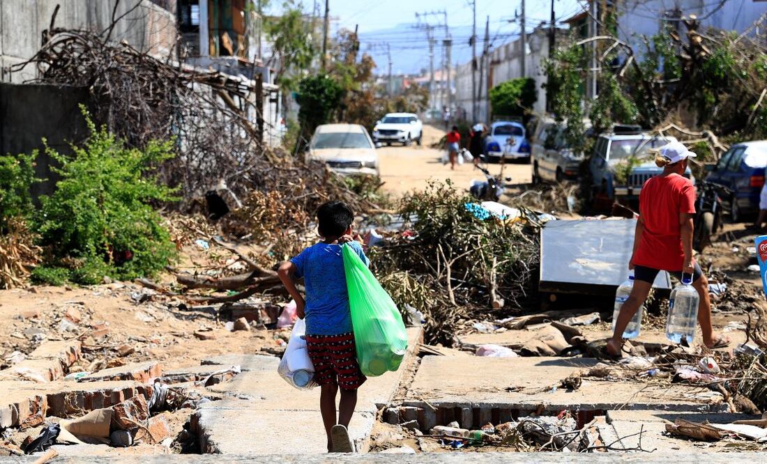 Damnificados caminan entre los escombros, en una de las zonas afectadas por el paso del huracán Otis, en el balneario de Acapulco, en el estado de Guerrero. FOTO: EFE