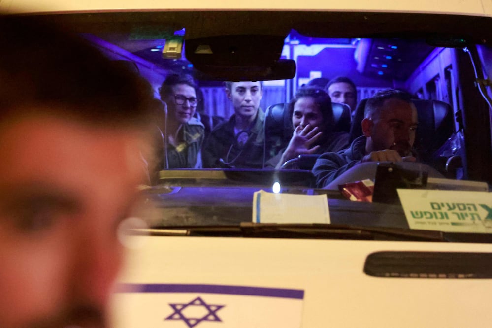 Una rehén israelí recién liberada saluda mientras se sienta entre los soldados cuando llegan dentro de una camioneta a la base militar de Ofakim en el sur de Israel a principios del 30 de noviembre de 2023, después de ser liberada de la Franja de Gaza. Foto AFP