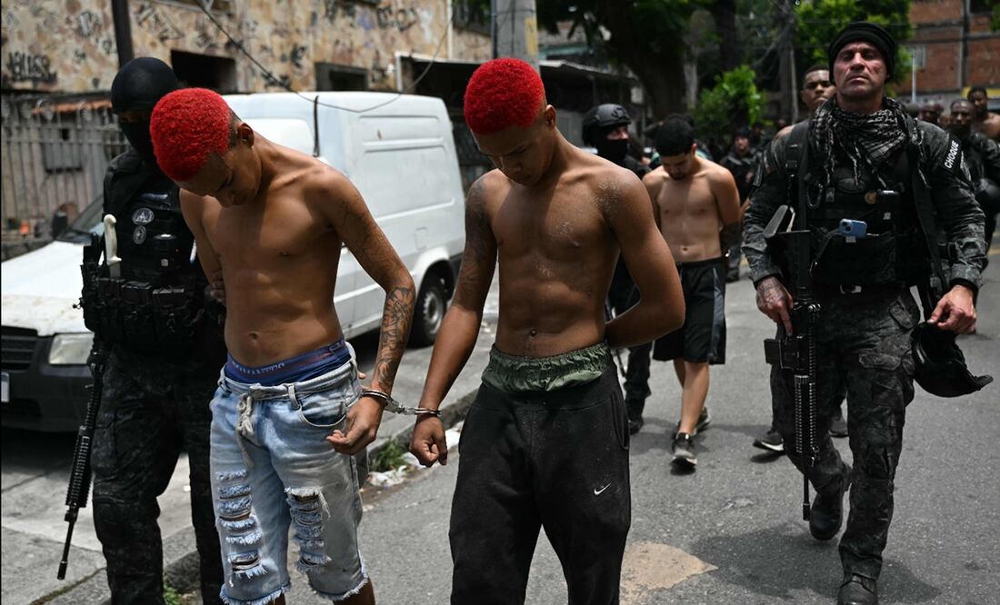 Agentes de policía escoltan a sospechosos arrestados durante la Operación Contención fuera de la favela Vila Cruzeiro, en el complejo Penha, Río de Janeiro, Brasil, el 28 de octubre de 2025. Foto: AFP