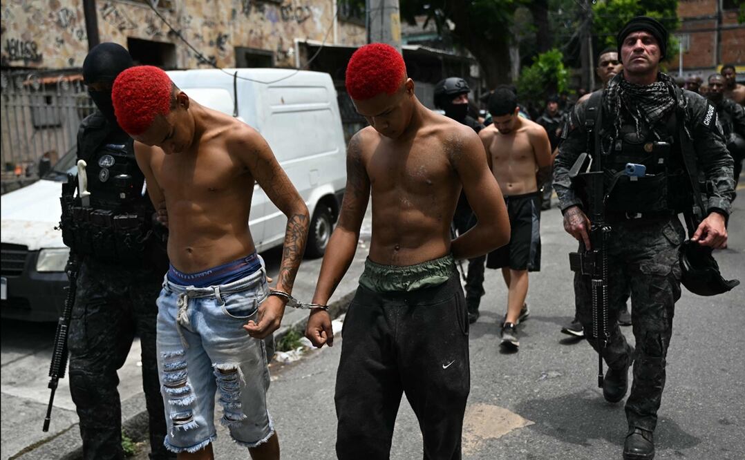 Agentes de policía escoltan a sospechosos arrestados durante la Operación Contención fuera de la favela Vila Cruzeiro, en el complejo Penha, Río de Janeiro, Brasil, el 28 de octubre de 2025. Foto: AFP
