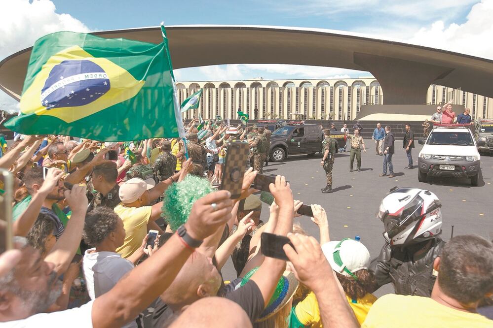 El presidente de Brasil, Jair Bolsonaro (en la camioneta blanca), saluda a docenas de simpatizantes reunidos afuera del cuartel general del ejército. Foto: JOÉDSON ALVES. EFE
