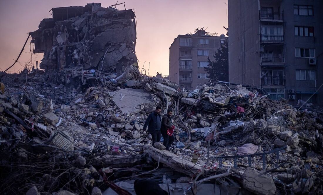 Dos hombres caminan sobre los escombros de los edificios derrumbados tras un fuerte terremoto, en Hatay, Turquía, el 13 de febrero de 2023. Foto: Martin Divisek/EFE