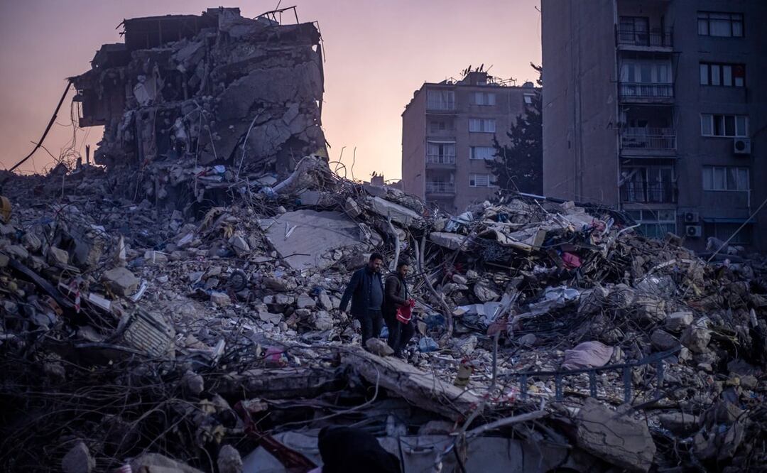 Dos hombres caminan sobre los escombros de los edificios derrumbados tras un fuerte terremoto, en Hatay, Turquía, el 13 de febrero de 2023. Foto: Martin Divisek/EFE