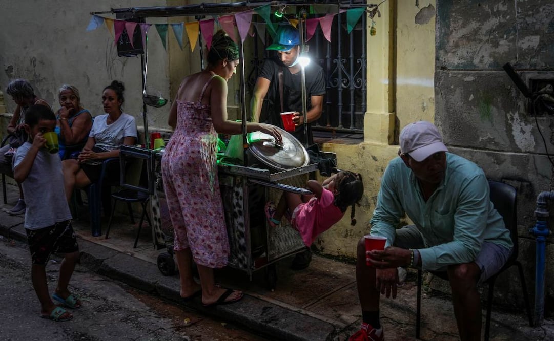 Una mujer compra sopa a un vendedor ambulante durante un corte de energía en La Habana, en 2024. Foto: AP