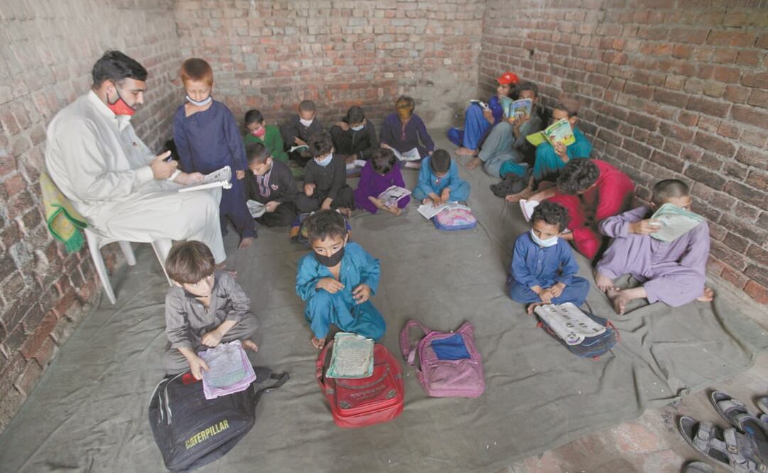 Niños refugiados afganos asisten a clases impartidas por un voluntario en un barrio a las afueras de Lahore, Paquistán. Foto: K.M. Chaudary. AP