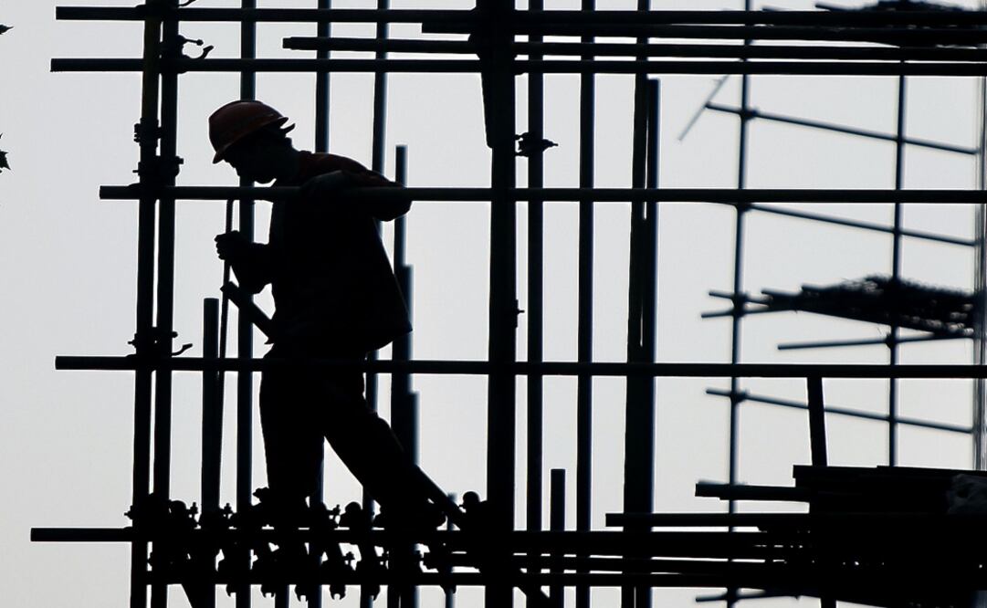 A construction worker walks on scaffolding at a construction site – Photo: Eugene Hoshiko/AP