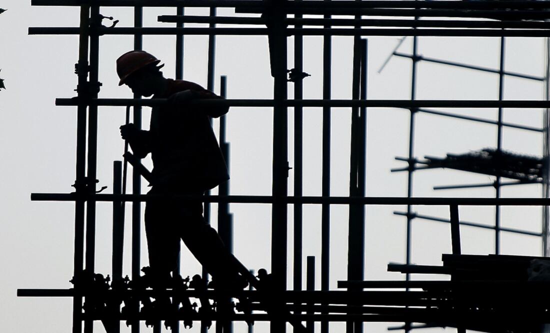 A construction worker walks on scaffolding at a construction site – Photo: Eugene Hoshiko/AP