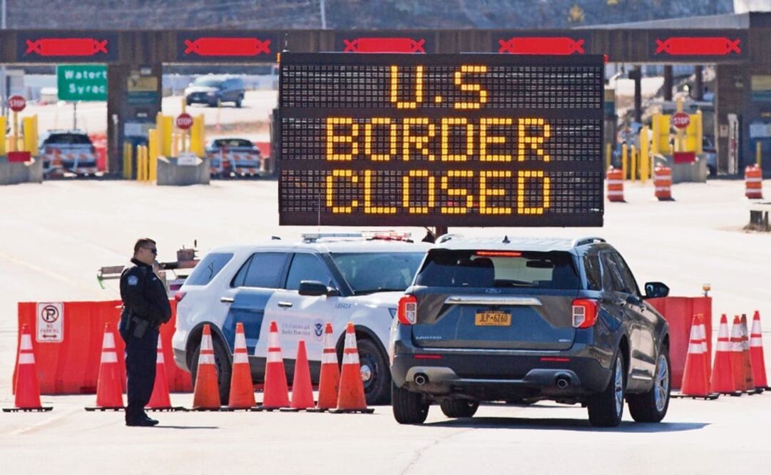 In this file photo US Customs officers speaks with people in a car beside a sign saying that the US border is closed at the US/Canada border - Photo: Lars Hagberg/AFP