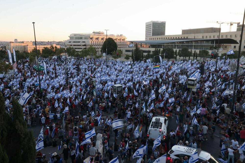 Los manifestantes ondean banderas israelíes mientras marchan en Jerusalén el 22 de julio de 2023, durante una marcha de varios días que comenzó en Tel Aviv para protestar contra el proyecto de ley de reforma judicial del gobierno antes de una votación en el Parlamento. Foto: AFP