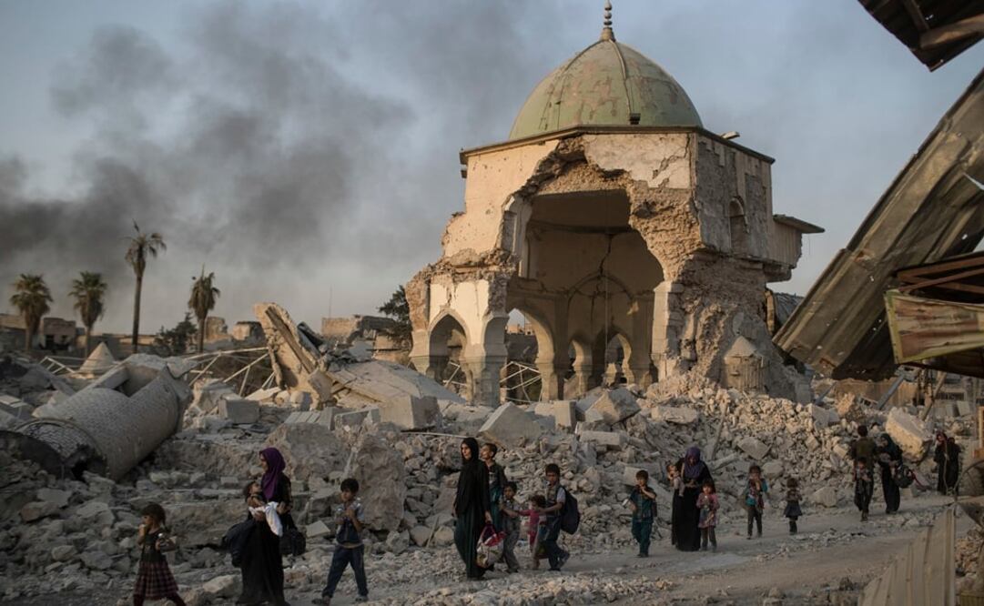 Civiles iraquíes que huyen de Mosul pasan por delante de la dañada mezquita al-Nuri. Foto: AP/Felipe Dana, archivo