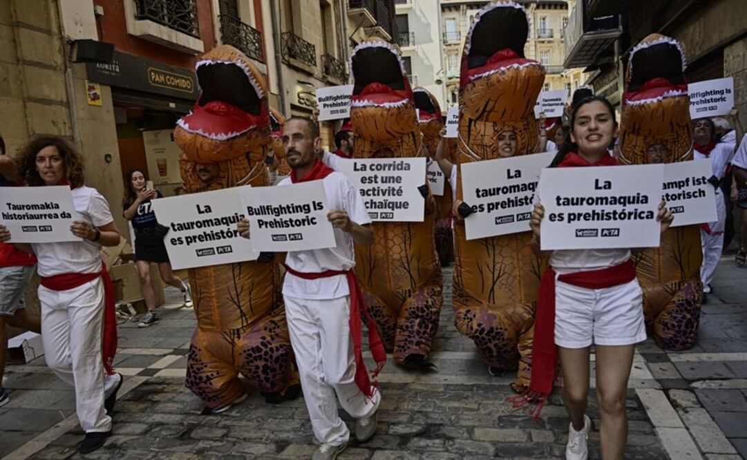 Personas disfrazadas como dinosaurios y con los colores blanco y rojo del Festival de San Fermín protestan contra la crueldad hacia los animales. Foto: AP