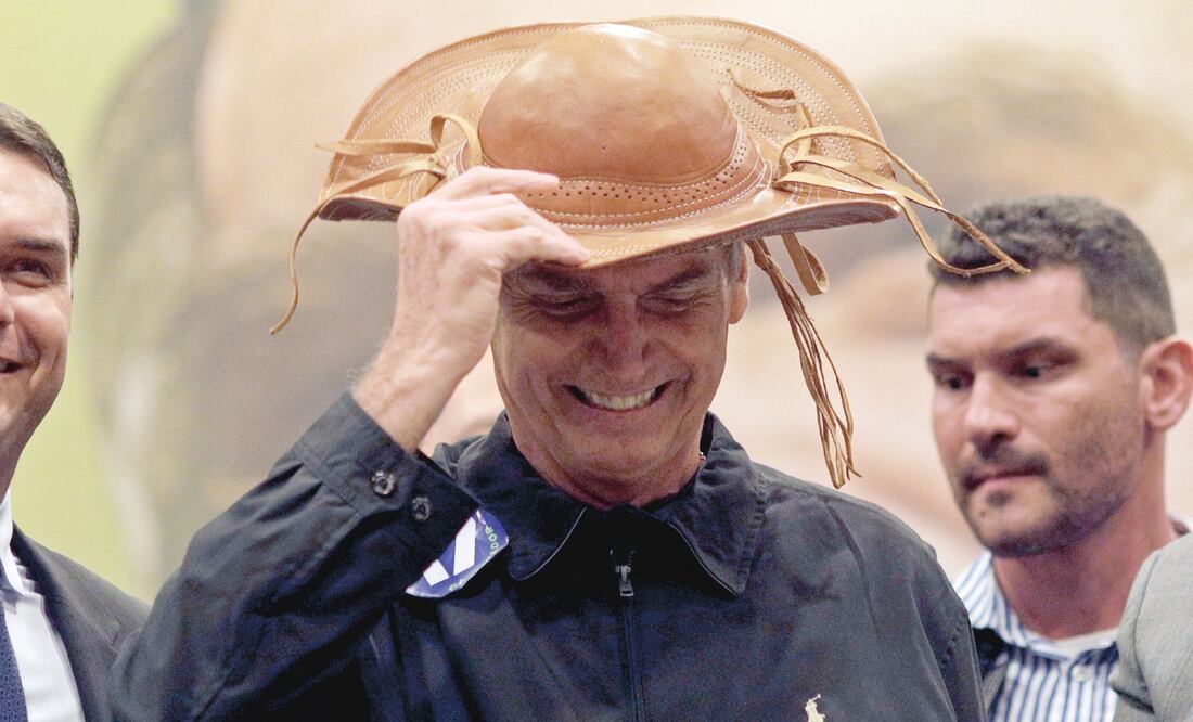 El candidato presidencial Jair Bolsonaro (centro), acompañado de su hijo Flavio (izq.), al llegar a una conferencia de prensa ayer en Río de Janeiro. Foto: RICARDO MORAES. REUTERS