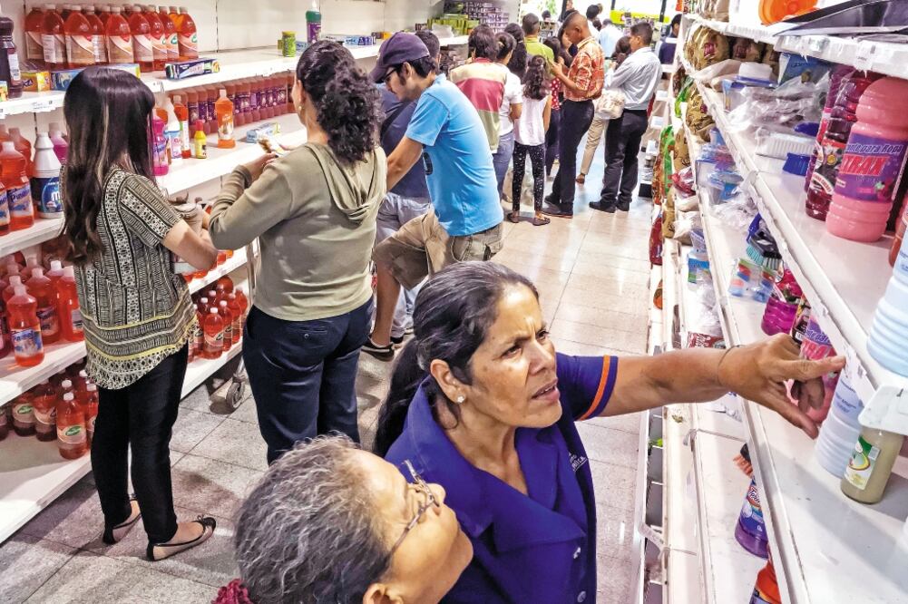 Personas revisan el costo de productos en un supermercado de Caracas, Venezuela. El gobierno busca ejercer un control de precios ante la crisis económica . (MIGUEL GUTIÉRREZ. EFE)