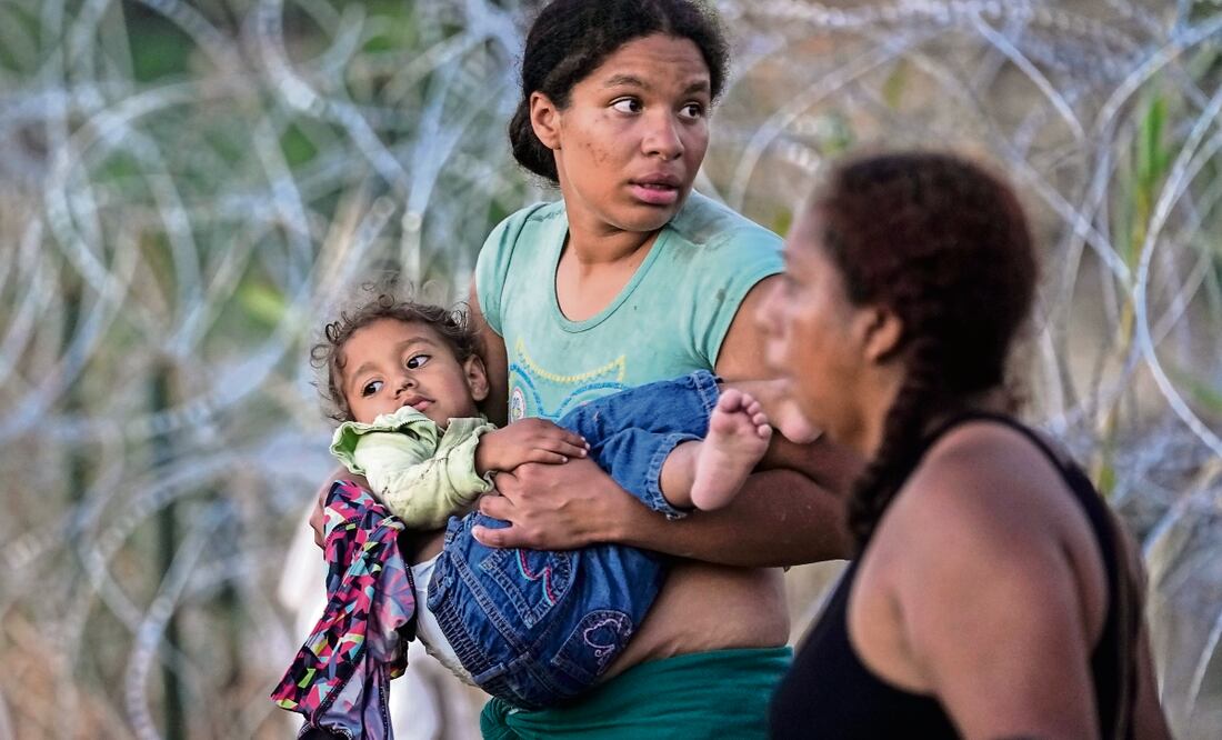Una mujer con su hijo, y otros migrantes cruzan el Río Grande (Bravo), al ingresar desde México a suelo estadounidense, donde esperan ser procesados por la CBP.  Foto: Eric Gay AP