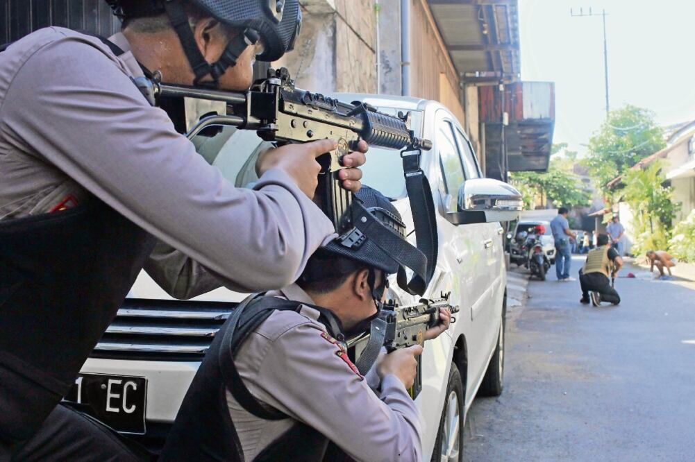 Policías de Indonesia apuntan a un sospechoso, luego del atentado en la estación de policía en Surabaya, ayer (REUTERS)