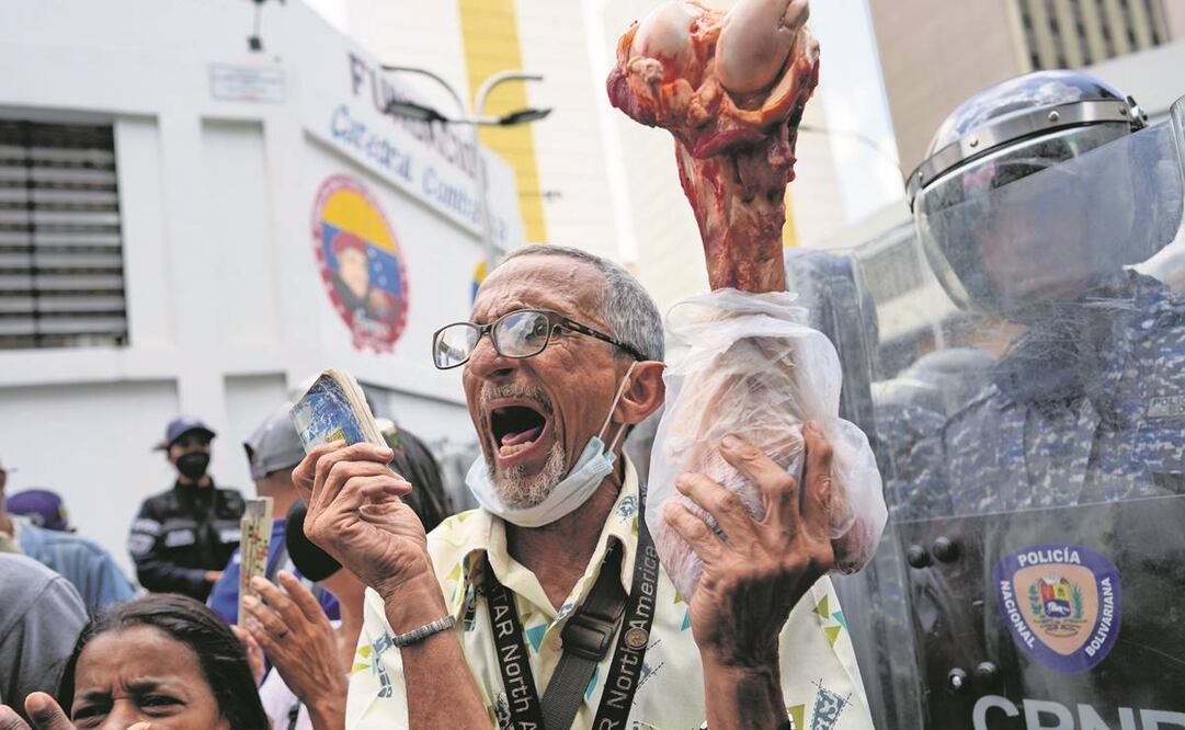 Un venezolano alza un pedazo de hueso durante una protesta por la pensión que reciben los adultos mayores y que, denuncian, no les alcanza para comer. Foto: Ariana Cubillos