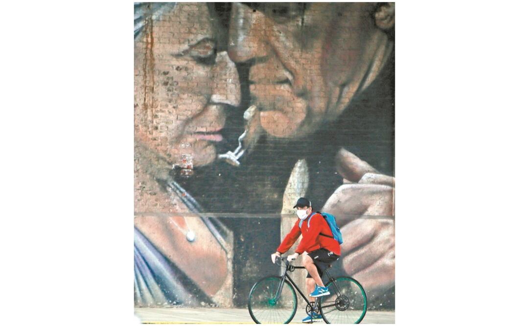 Frente a un mural que representa a una pareja de la tercera edad, un ciclista con cubrebocas transita en Buenos Aires, Argentina, donde en la última semana se ha elevado la cifra de denuncias por violencia doméstica. JUAN IGNACIO RONCORONI. EFE
