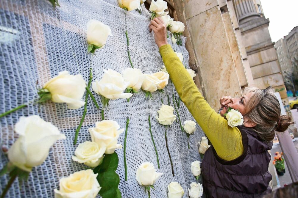 Una colombiana coloca rosas de la paz en un edificio del gobierno (IVÁN VALENCIA. AP)