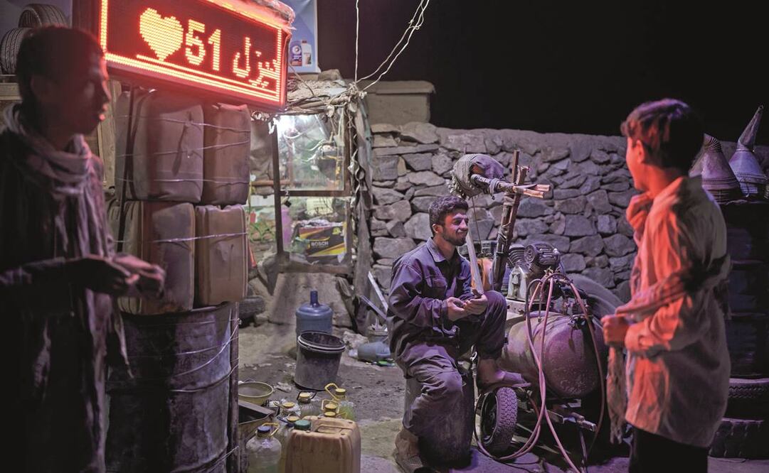 Un hombre conversa con niños mientras espera a los clientes al costado de una carretera en Kabul. Foto: Felipe Dana. AP