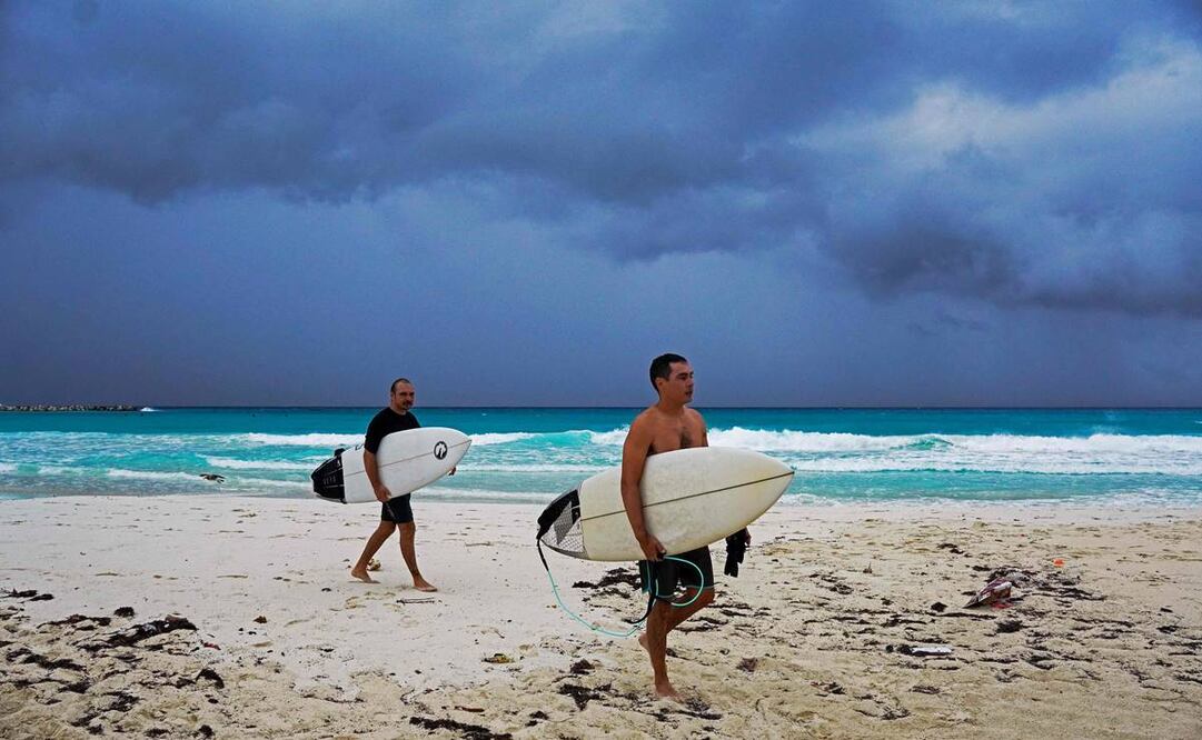 Surfistas abandonan la playa antes de la llegada del huracán Helene a Cancún. Foto: AFP