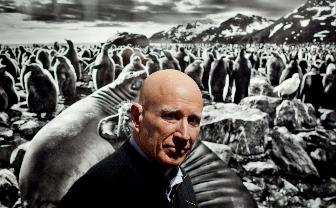 El fotógrafo brasileño Sebastião Salgado posa frente a una imagen de su exposición "Génesis" en el Museo de Historia Natural de Londres, el martes 9 de abril de 2013. Foto: AP