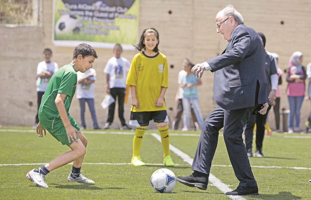 Joseph "Sepp" Blatter juega con unos niños en la inauguración de una cancha de futbol en Dura Al-Qari, cerca de la ciudad cisjordana de Ramalá, el 20 de mayo pasado (MADJI MOHAMMED / AP)