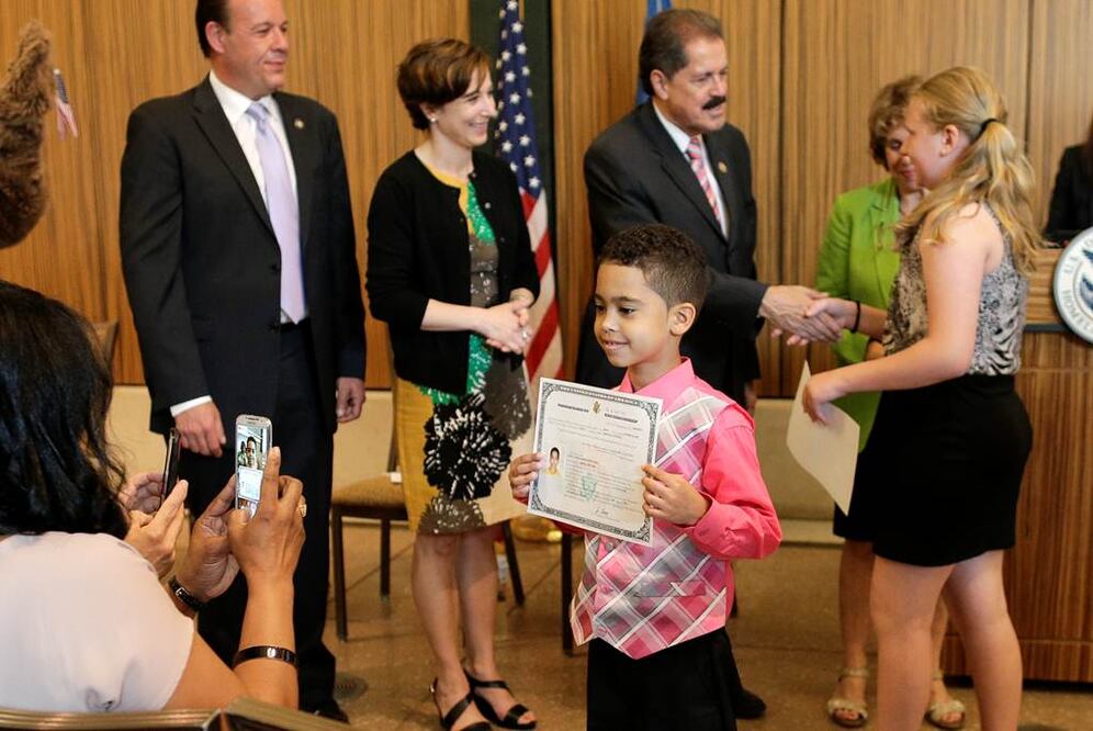 Irving Morán, originario de República Dominicana, muestra su certificado de ciudadanía, durante una ceremonia en el zoológico del Bronx en NY