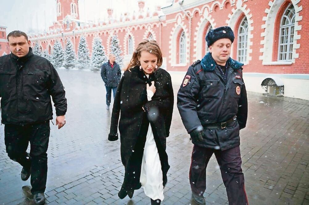 Ksenia Sobchak, candidata a la presidencia rusa, junto a policías, luego de que un desconocido la empujó y le aventó agua (AP)
