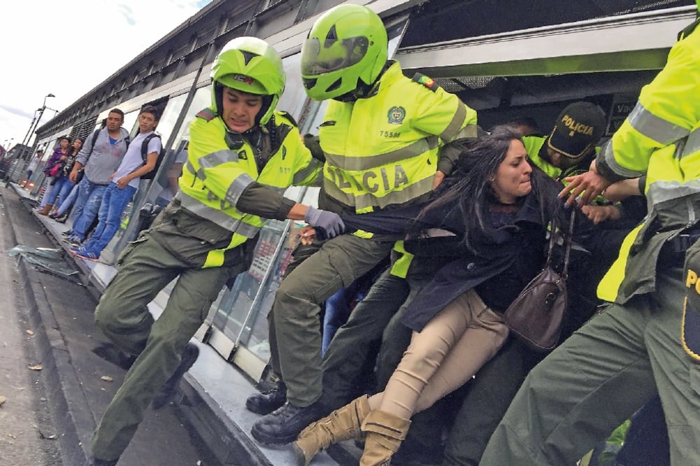 Policías detienen a una manifestante durante una protesta de usuarios del sistema de transporte TransMilenio en el sector de Patio Bonito en el sur de Bogotá (JUAN PÁEZ. XINHUA)