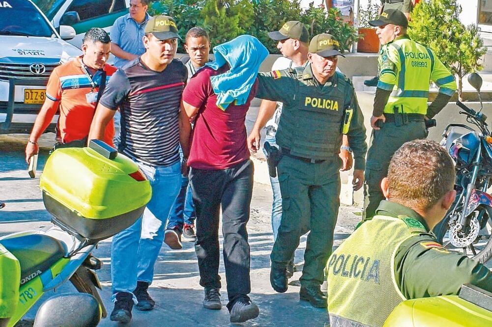 Policías escoltan a un sospechoso de estar tras el ataque ocurrido ayer en Barranquilla, que dejó cinco oficiales muertos (AFP)