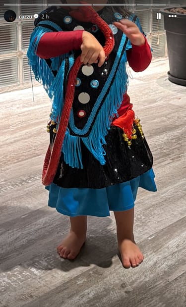 Inti aparece vestida con un atuendo parecido al que usa Cazzu en su video "Jujuy Estrellado": de colores vivos, rojo, azul y negro además de flecos azules y detalles brillantes.
Su atuendo incluye botones grandes decorativos al frente, así como cinturón rojo con cascabeles dorados. Una serpiente roja de juguete como accesorio.