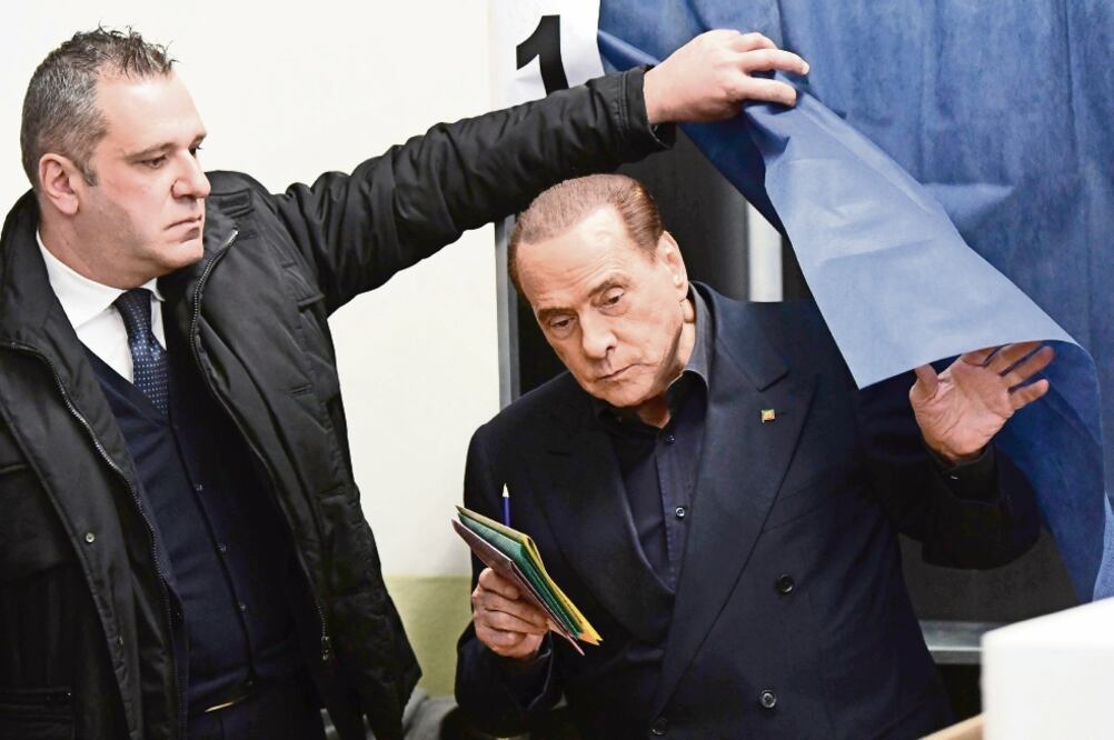 Silvio Berlusconi, ex premier italiano, votó ayer en Milán. Una activista con el torso desnudo protestó contra él (MIGUEL MEDINA. AFP)