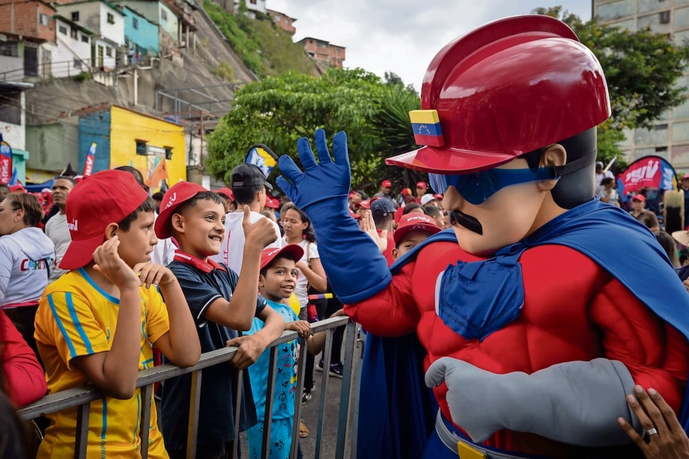 Un hombre con el disfraz de Súper Bigote saluda a niños durante una marcha chavista , en Caracas. Foto de Rayner Pena R. EFE
