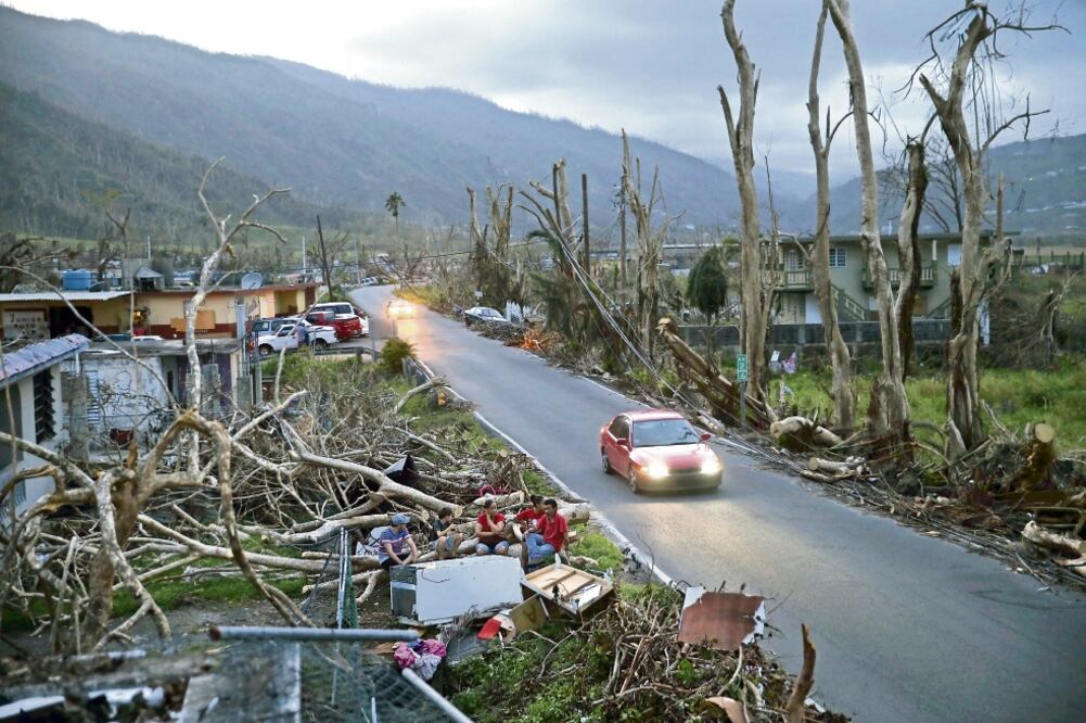 Vecinos sentados sobre los escombros de sus casas en Yabucoa, Puerto Rico. Nueve días después del azote del huracán María, los habitantes aún no tienen luz, ni agua corriente ni telecomunicaciones (GERALD HERBERT. AP)