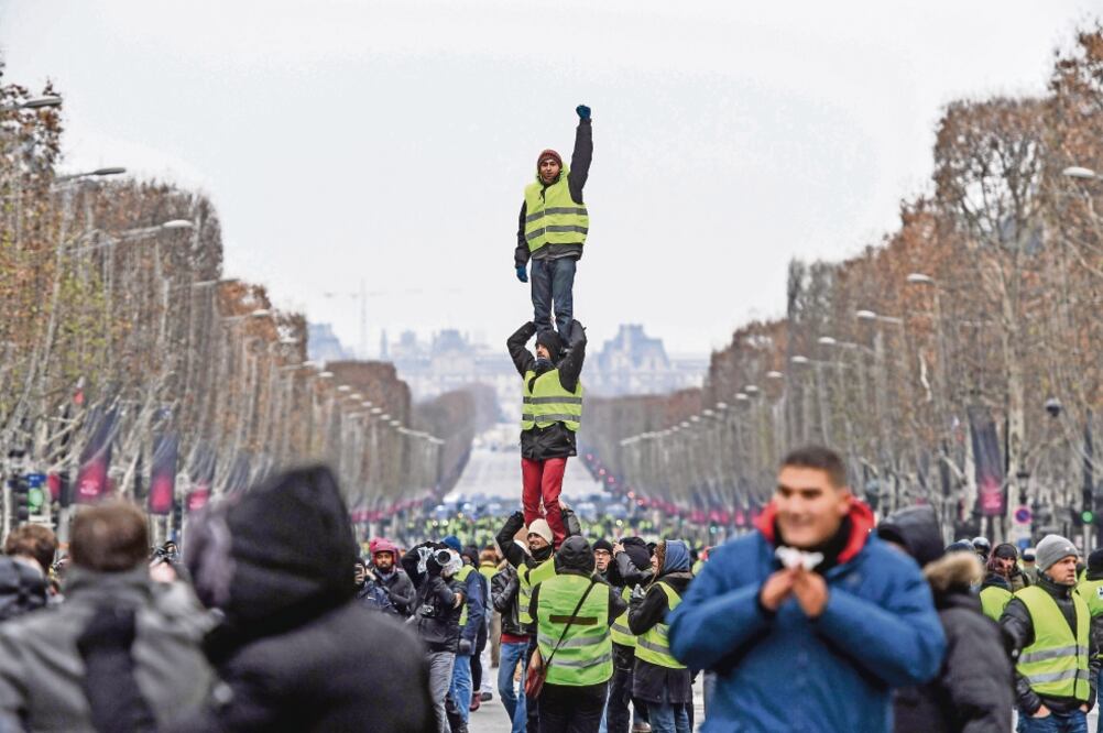 Algunos chalecos amarillos formaron una pirámide humana durante su protesta de ayer en París contra el gobierno y el costo de la vida en Francia. (CHRISTOPHE ARCHAMBAULT. AFP)