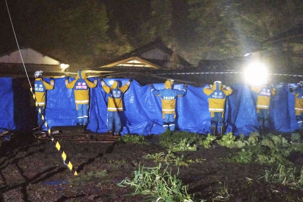 La policía usa plásticos azules para ocultar el rescate de una mujer de 90 años en Suzu, Ishikawa. Foto: AP