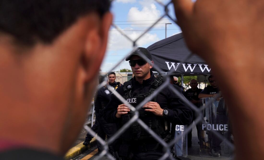 A young asylum seeker grasps the gate of the Gateway International Bridge as U.S. Customs and Border Protection agents guard the port of entry – Photo: Verónica G. Cárdenas/REUTERS