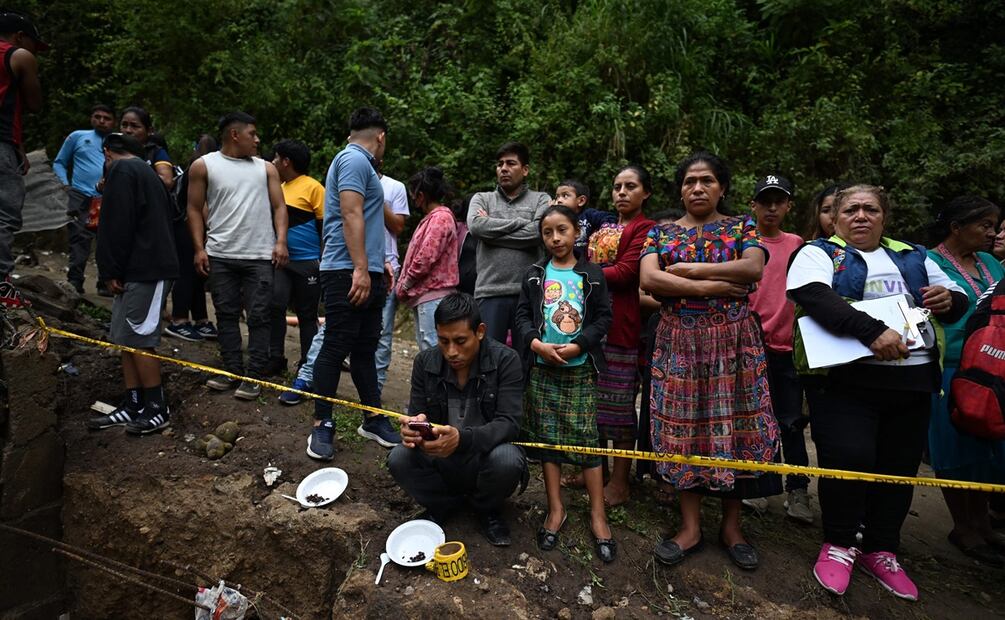 La gente observa cómo los equipos de rescate trabajan en el lugar donde un río contaminado con aguas residuales crecido por las fuertes lluvias arrasó con viviendas precarias en el barrio de chabolas Dios es Fiel. Foto: AFP