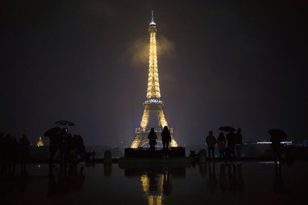 Personas se reunieron ayer en la Plaza del Trocadero para ver el momento en el que la Torre Eiffel se iluminó en memoria de las víctimas del atentado en Marsella y de la masacre en Las Vegas, Estados Unidos. (KAMIL ZIHNIOGLU. AP)