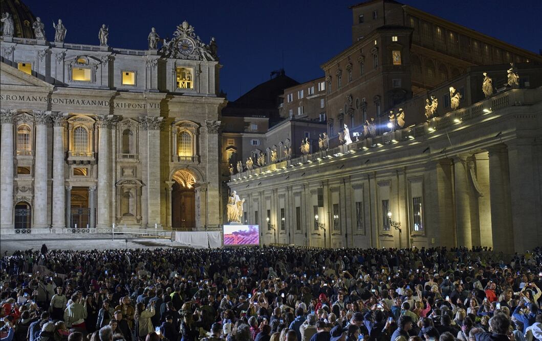 Asistentes observan una columna de humo negro salir de la chimenea de la Capilla Sixtina, en el primer día de cónclave, que indica que no se eligió a un nuevo papa, en la Plaza de San Pedro, el 7 de mayo de 2025. Foto: AFP