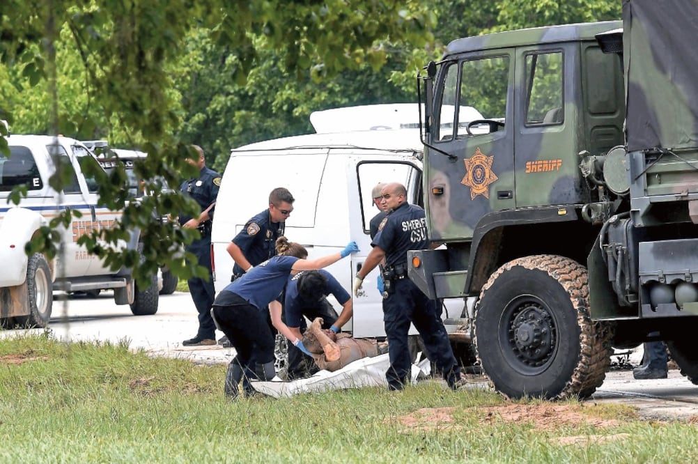 Investigadores remueven uno de los seis cuerpos de una familia que fueron hallados en una camioneta que se llevó el agua en Houston. (MARK RALSTON. AFP)