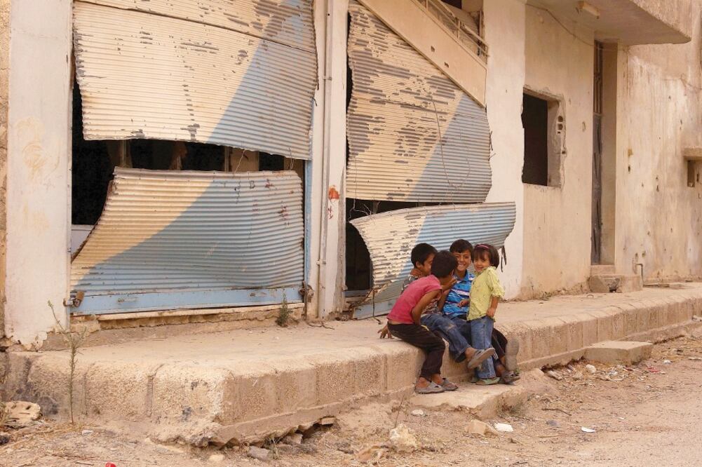 Niños sirios afuera de comercios semidestruidos en la ciudad de Deraa, donde han ocurrido este año combates entre rebeldes y fuerzas gubernamentales (ALAA AL-FAKIR. REUTERS)