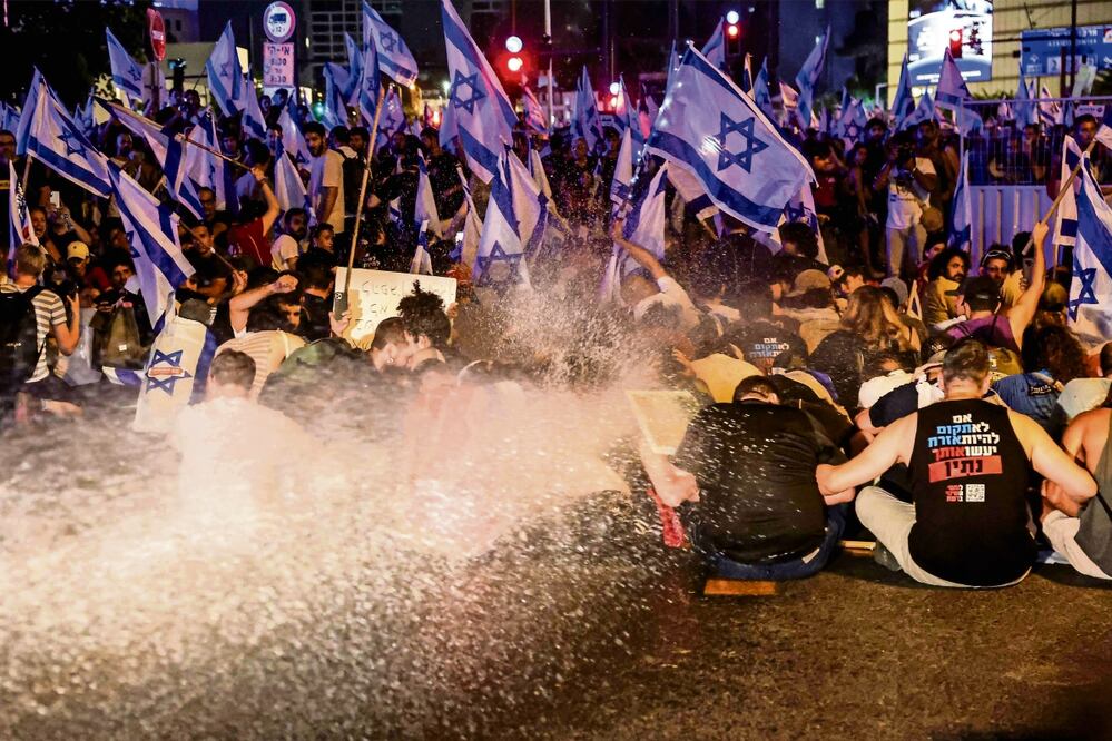 Policías antimotines arrojan agua a manifestantes durante una protesta contra la reforma judicial del premier Benjamin Netanyahu, en Tel Aviv. Foto: Jack Guez / AFP