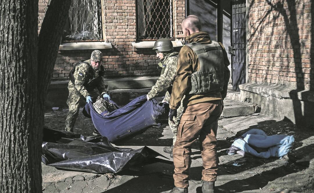 Personal de emergencia en Ucrania remueve el cuerpo de un efectivo, tras un ataque en un instituto de investigación en Kiev. Foto: ARIS MESSINIS. AFP