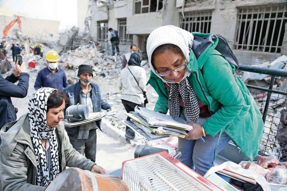 Personas en Teherán con algunas pertenencias que fueron encontradas entre los escombros.  12 de marzo de 2026 Crédito: Xinhua/Shadati.