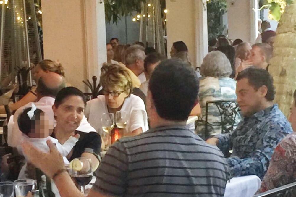 En imágenes tomadas el 20 de marzo de 2016, Alejandra Barrales, con su hija en brazos, es acompañada por cuatro hombres con quienes comparte una botella de vino y otras bebidas en el restaurante que está a escasos metros del mar (ESPECIAL)