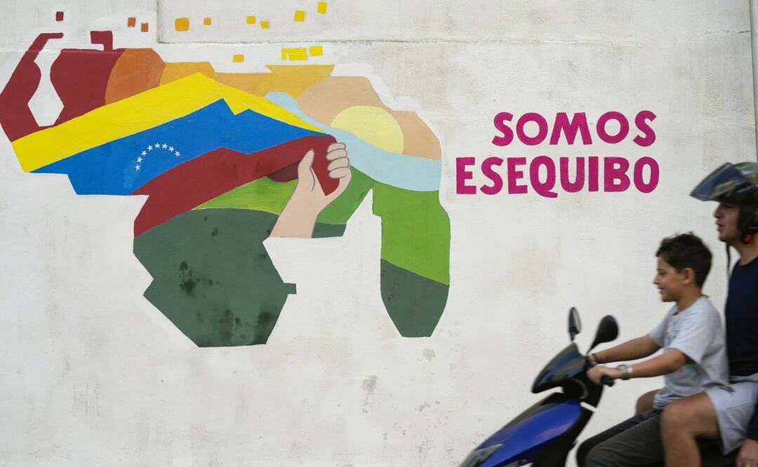 Un niño conduce una motocicleta por delante de un mural con el mapa de Venezuela, que incluye el territorio de Esequibo. Foto: AP