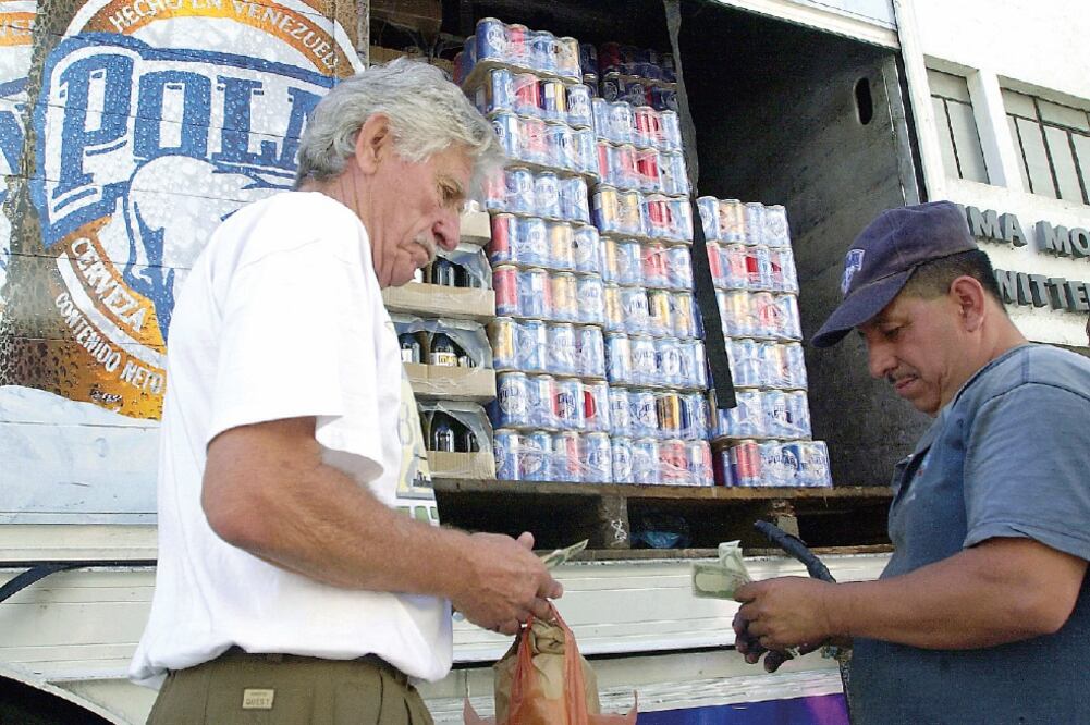 Un venezolano compra cerveza a un camión repartidor. El viernes cerró la última planta de producción de La Polar (ARCHIVO AP)