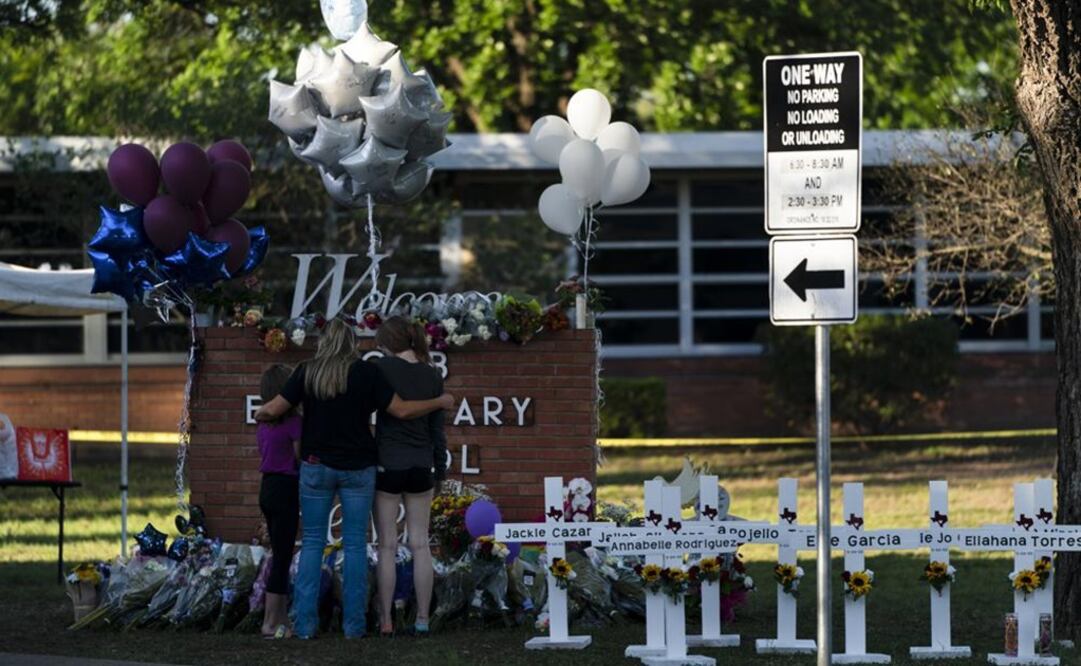 Una familia rinde homenaje frente a las cruces que llevan los nombres de las víctimas en la escuela primaria Robb en Uvalde. Foto: AP 