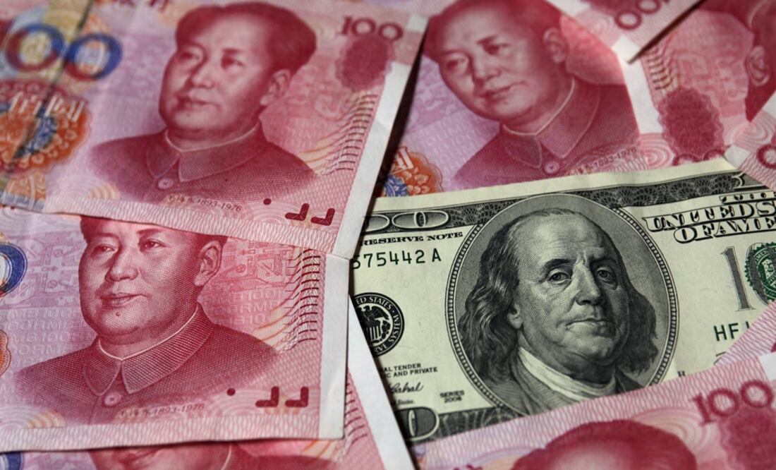 A U.S. $100 banknote is placed next to 100 yuan banknotes – Photo: Petar Kujundzic/REUTERS